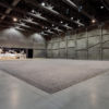 Installation view at the Marciano Foundation featuring a vast floor of porcelain sunflower seeds leading to a distant room with Life Cycle figures hanging as if flying