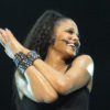 Closeup of Janet Jackson with microphone headset on over smile, in concert in 2011